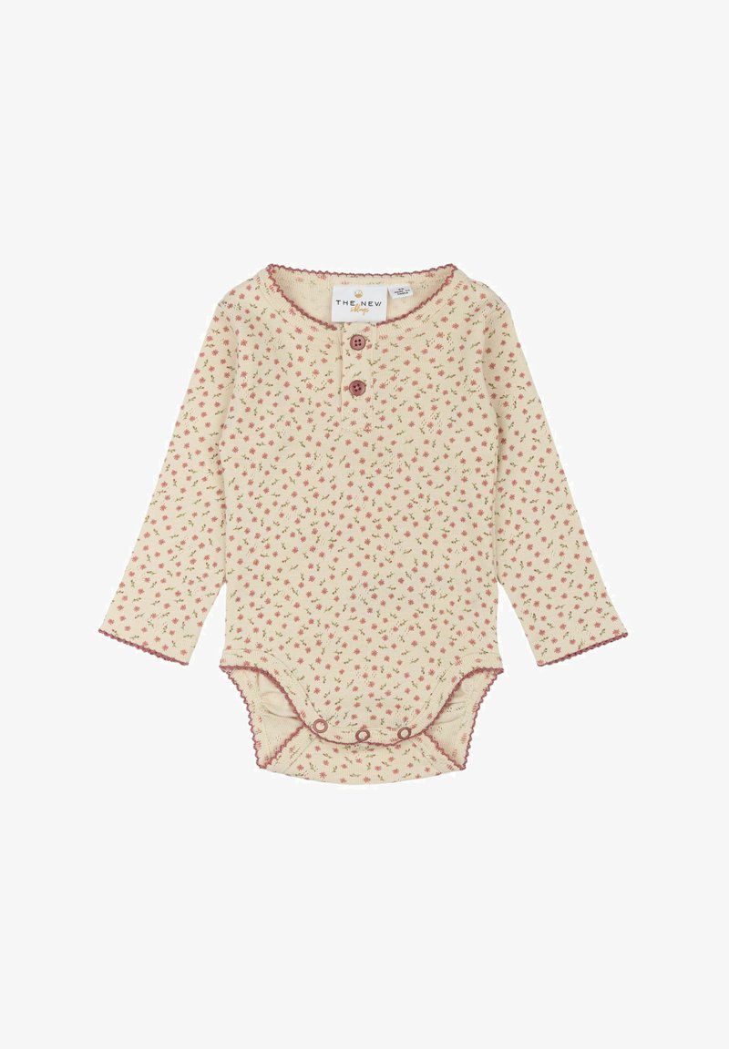 Long-sleeve baby bodysuit in cream with pink floral pattern, ribbed texture, two button closure, and scalloped edges.