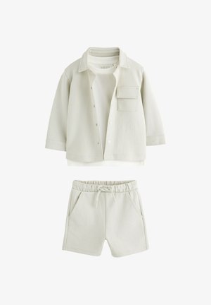 Completo casual beige chiaro con camicia a maniche lunghe con bottoni e taschino sul petto e pantaloncini con vita elasticizzata con coulisse e tasche laterali.