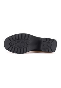 Semelle de botte noire avec des crampons profonds, motifs circulaires et rectangulaires sur un fond blanc uni.