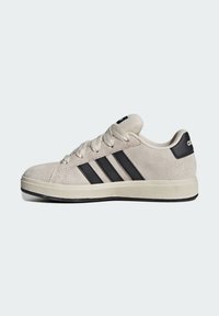 Beige mockask sneaker med svarta tre ränder, rund tå, texturerad gummisula och kontrasterande svart hälaccent. Klassisk snördesign.