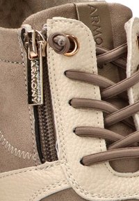 Zapatilla de gamuza beige con un panel texturizado en color crema, cordones redondos y una cremallera lateral con un detalle en tono dorado. Presenta sutiles detalles de costura.
