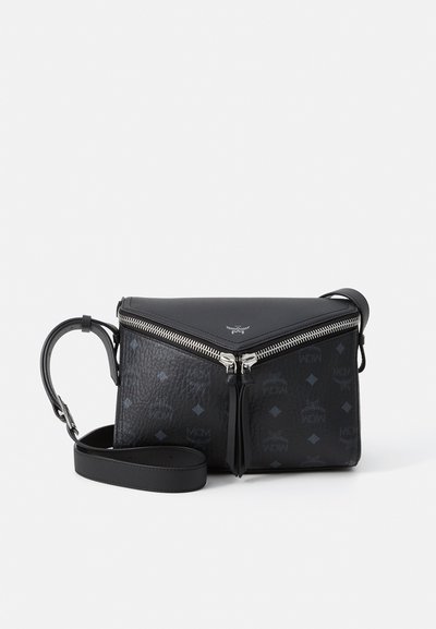 Bolso de cuero negro tipo bandolera con cremallera en forma de V plateada, patrón de logo grabado y correa ajustable sobre fondo blanco.