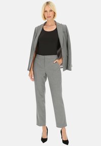 Szary garniturowy żakiet na czarnej bluzce, spodnie w kolorze szarym z wysokim stanem i czarne szpilki. Teksturowana tkanina z wyraźnymi liniami i zorganizowanym krojem.