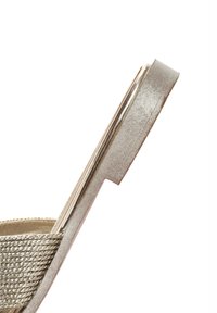 Metalen gouden wedge sandaal met een gestructureerde band, een gladde zool en een slank ontwerp, met een ronde neus en minimalistische accenten.