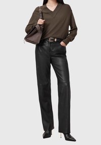 Ciemnozielony sweter z dekoltem w serek, czarne spodnie ze skóry o prostych nogawkach oraz czarne szpilki w szpic. Do tego szare torebka na ramię.