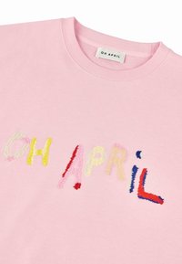 Rosa Sweatshirt mit mehrfarbigem, gesticktem Text "OH APRIL". Der Stoff ist weich, mit einem gerippten Ausschnitt und einem lässigen Design.