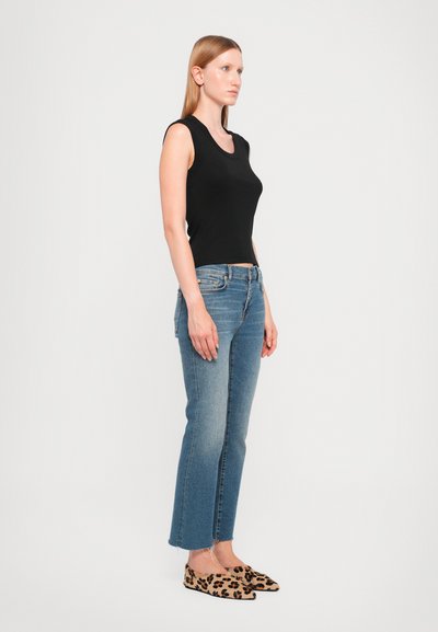 Black sleeveless top, blue jeans, and leopard print slip-on shoes. The jeans are slightly cropped with a slight fray at the hem.