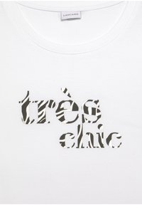 Weißes Baumwoll-T-Shirt mit dem Satz "très chic" in einer Kombination aus schwarz-weiß gestreiften Buchstaben mit silbernen Akzenten.
