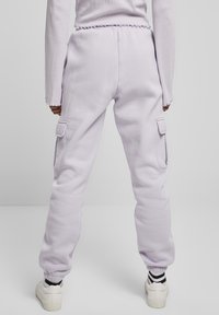 Fioletowe spodnie dresowe typu cargo z elastycznym pasem, bocznymi kieszeniami i ściągaczami u dołu. Wykonane z miękkiego materiału, charakteryzujące się luźnym krojem.