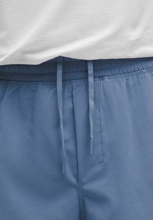 Light blue shorts with an elastic waistband, featuring a drawstring and soft texture. A white, ribbed top partially visible above.