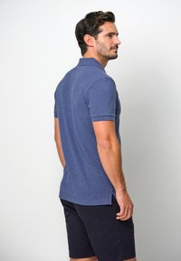 Navyblå pikétröja i texturerat tyg, med korta ärmar, krage och sidofickor, som matchas med mörka shorts.