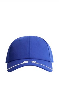 Blå basebollkeps med en enkel design, platt skärm och textilstruktur. Har vita accentlinjer längs framkanten.