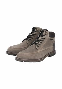 Botas de tobillo de ante marrón con cordones negros, cuello acolchado y suela de goma marrón en contraste. Los detalles de costura realzan el diseño.