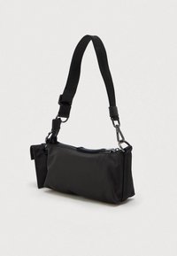 Μικρή μαύρη ορθογώνια τσάντα ώμου με ρυθμιζόμενο λουρί και κύριο θάλαμο με φερμουάρ σε απλό φωτεινό φόντο.