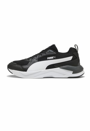 Zwarte Puma sportschoen met witte zool, witte zijstreep, zwarte veters en Puma-logo aan de zijkant, gezien van links.