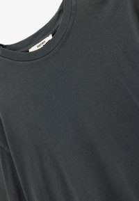 Mørkegrå bomulds T-shirt med rund halsudskæring og korte ærmer. Har en glat tekstur og minimale sømdetaljer. Mærkeskilt synligt.