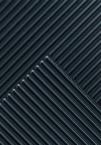 Material blu scuro testurizzato con costole parallele. Le sezioni si incontrano ad un angolo, creando un contrasto nei motivi. Superficie liscia con scanalature strette.