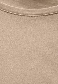 Beiger Baumwollstoff mit glatter Textur und rundem Ausschnitt. Feines Strickmuster mit kleinen, subtilen Farbvariationen.