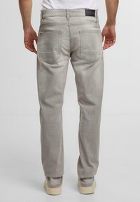 Jeans in denim grigio chiaro con vestibilità dritta, dotati di due tasche posteriori, cuciture sottili e un'etichetta brandizzata in vita.