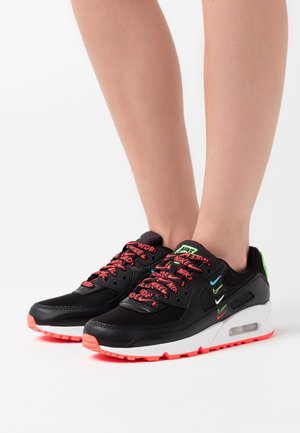 Černé sportovní boty z prodyšných síťovaných a syntetických materiálů, s výraznými červenými a zelenými akcenty, výrazným logem a viditelnou vzduchovou jednotkou.