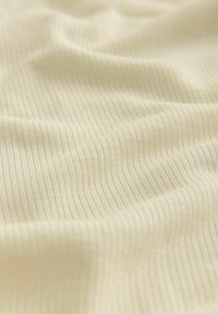 Soft, light yellow fabric with a fine ribbed texture, featuring subtle waves and folds, indicating its pliability and smoothness.