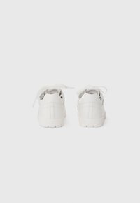 Weiße Sneaker mit einem Obermaterial aus glattem Leder, runder Spitze und Schnürdesign; verfügen über dezente Branding-Elemente und eine strukturierte Gummisohle.