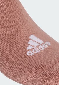Calcetín de color rosa claro hecho de un tejido texturizado, con un logotipo blanco de adidas en el costado. Acabado liso y un ajuste ceñido alrededor del tobillo.