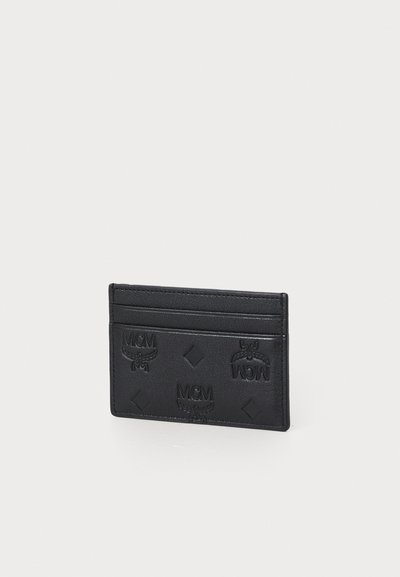 Svart lær kredittkortmappe med preget MCM-logo, som har en glatt tekstur, slank design og flere kortlommer på den ene siden.