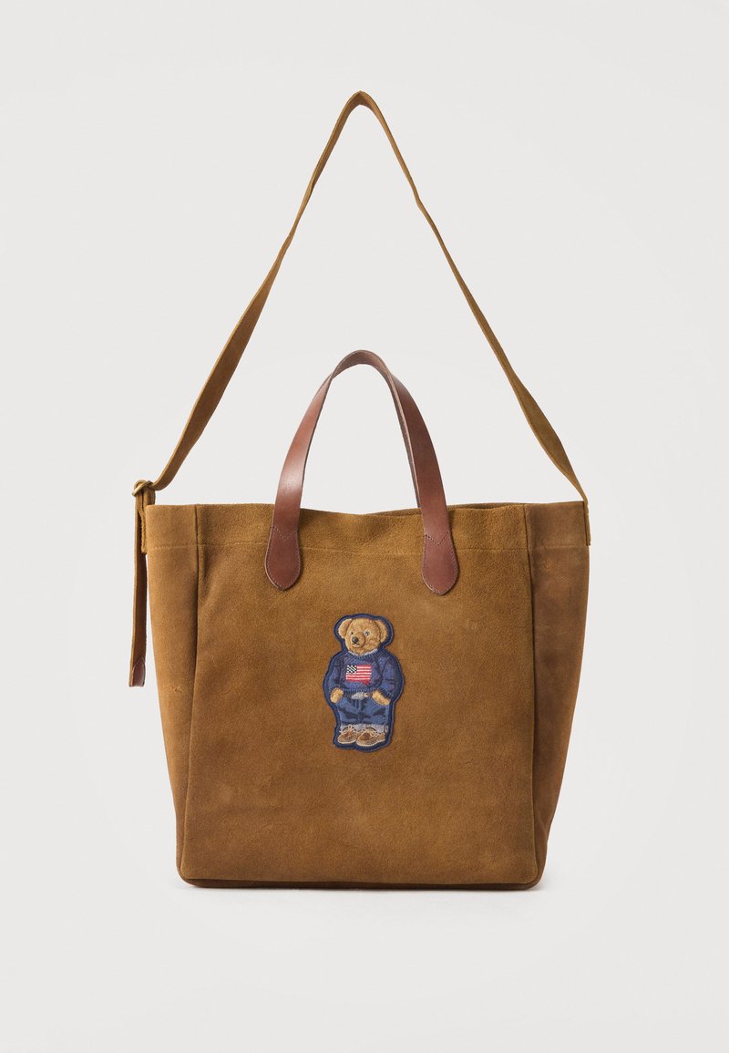 Borsa tote in camoscio marrone con doppi manici in pelle e tracolla regolabile, decorata con un orsetto che indossa un maglione blu e tiene una toppa con la bandiera americana.