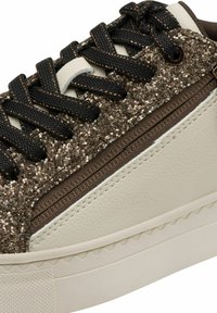 Sneaker con un upper in pelle beige testurizzata e accenti glitterati in bronzo. Presenta lacci neri e una suola in gomma con un design a onda.