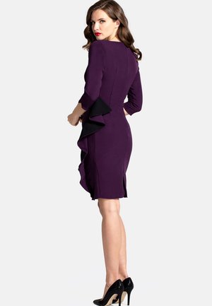 Purple dress with a fitted silhouette, black ruffles along the side, three-quarter sleeves, and a knee-length hem. Pair of black high heels.