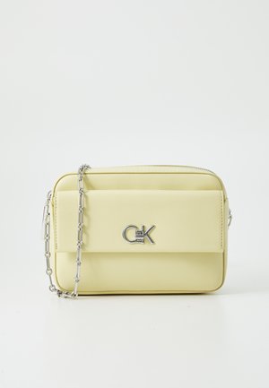 Yellow faux leather crossbody bag with a silver chain strap, featuring a front pocket and a prominent metallic logo detail.