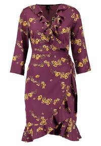 Robe portefeuille en tissu violet profond avec imprimé floral jaune, encolure froncée, manches trois-quarts et ourlet à volants.