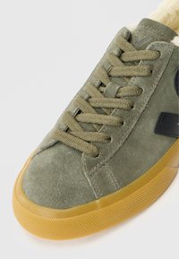 Tenisi din suede verde măsliniu, cu talpă din cauciuc texturat, având închidere cu șireturi plate și un accent din piele neagră pe lateral.