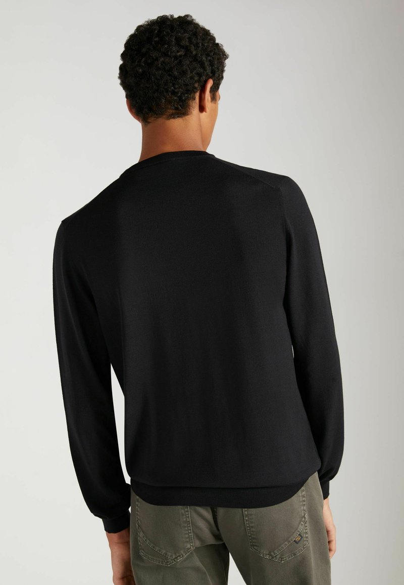 Pull noir à manches longues avec un col rond et des poignets côtelés, montré de dos, fabriqué à partir d'un tissu lisse et léger.