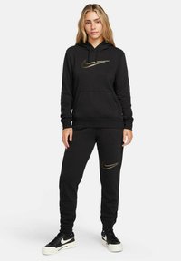 Černá mikina s kapucí a tepláky z měkké látky, s zlatým logem Nike na hrudi a stehně, s kapucí na šňůrku a kapsami.