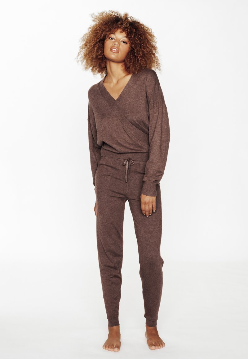 Ensemble de détente marron en tissu doux, comprenant un haut à encolure en V croisé et un pantalon fuselé avec une taille à cordon, au texture lisse.