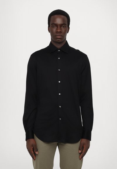 Chemise noire à manches longues avec col classique, fermeture à boutons à l'avant avec des boutons contrastants, tissu lisse et coupe ajustée.