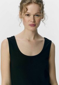 Top senza maniche di colore nero, con scollatura a barca, design aderente e tessuto morbido, caratterizzato da una silhouette sagomata.