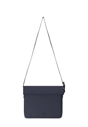 Navy blue rectangular crossbody bag with flap closure and adjustable strap, hanging against a white background.