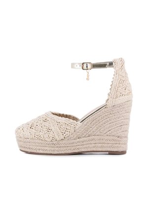 Sandalia cuña beige tejida con plataforma de yute trenzado y correa metálica en el tobillo con una pequeña hebilla dorada y charm.