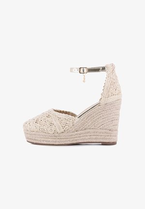 Sandalia cuña beige tejida con plataforma de yute trenzado y correa metálica en el tobillo con una pequeña hebilla dorada y charm.