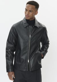 Black leather jacket with a smooth texture, zip closure, and a classic collar. Slim fit with side pockets and subtle stitching details.