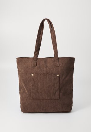 Sac cabas en velours côtelé marron avec longues anses et poche avant sécurisée par deux petits rivets métalliques.