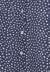Camisa azul-marinho com um padrão branco disperso, apresentando botões redondos e uma textura suave. Design simples com um estilo clássico de abotoamento.