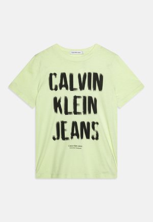 T-shirt di cotone verde chiaro con una grafica testuale nera audace "CALVIN KLEIN JEANS." Maniche corte e scollatura a girocollo.