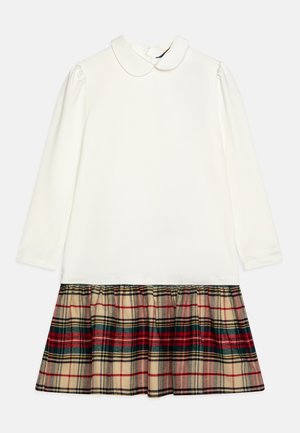 Weißes Langarmkleid mit Rundkragen, das einen karierter, ausgestellt Rock in Rot, Grün und Beige hat. Glatte Oberseite mit gerafften Ärmeln.