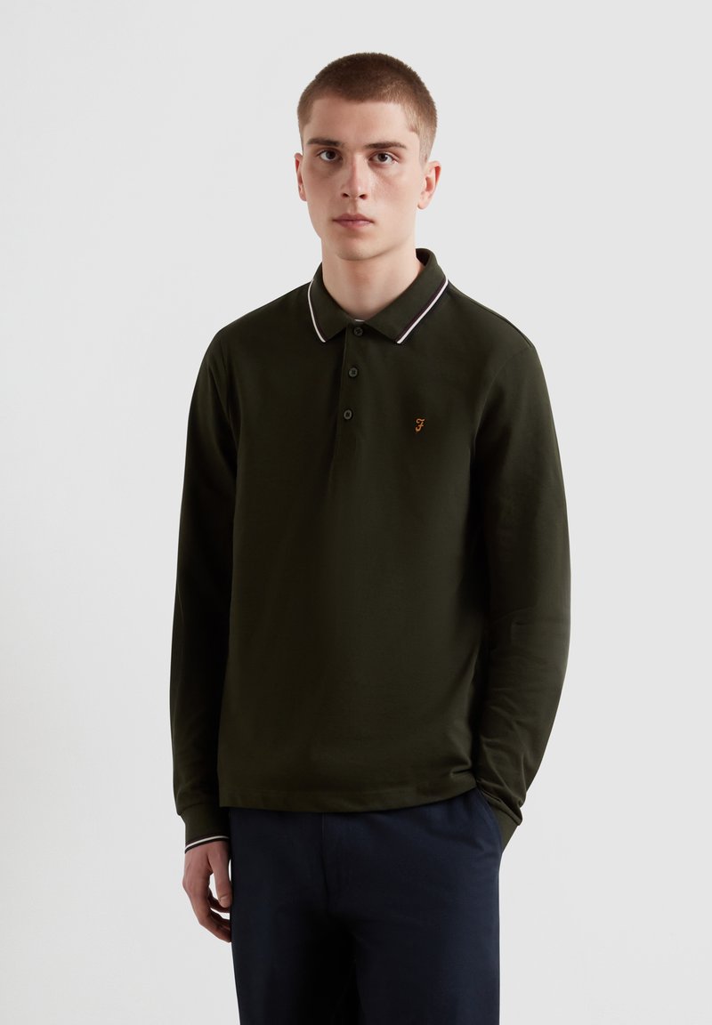 Dunkelgrünes Langarm-Poloshirt mit Kragen, versehen mit weißen Akzentstreifen und einem kleinen orangefarbenen Logo auf der linken Brust. Weiches Material.