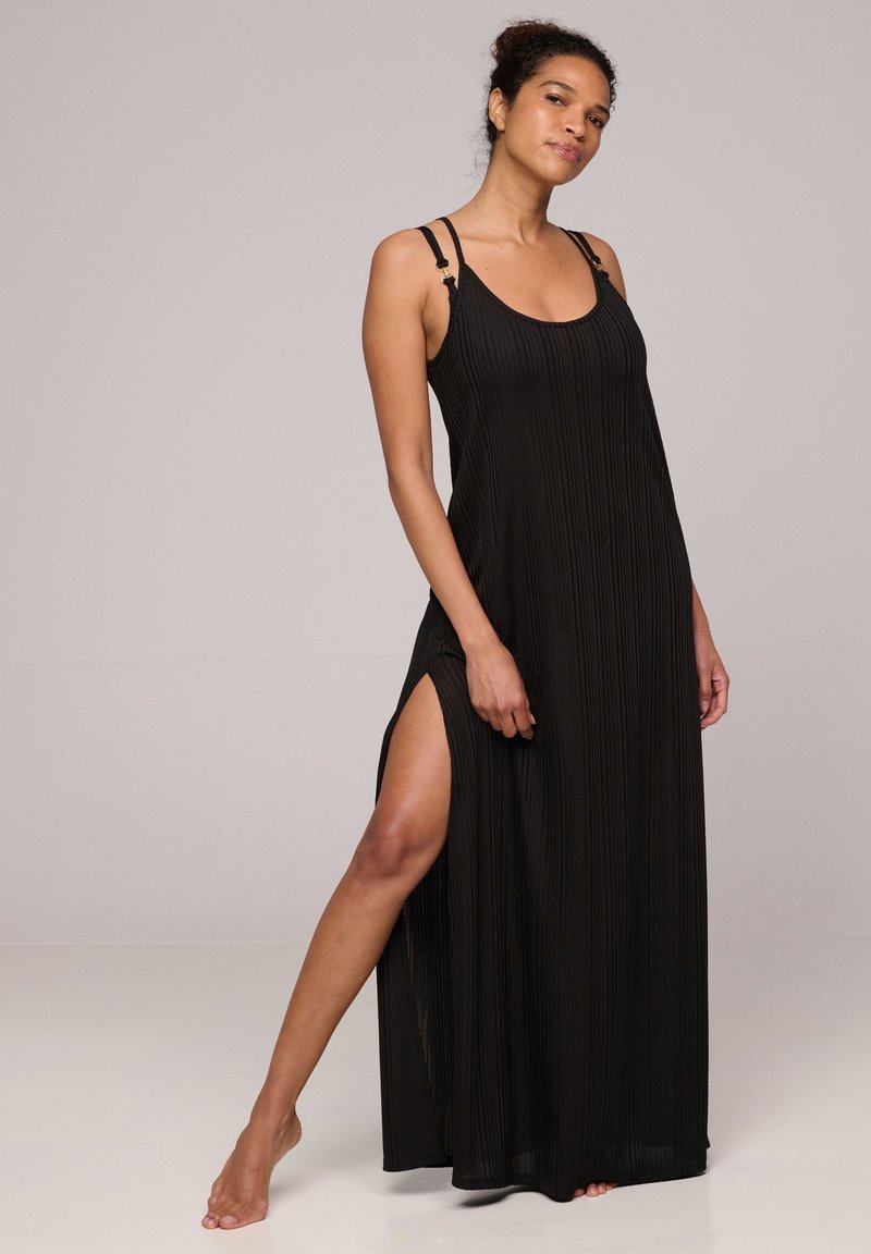 Abito lungo nero con pieghe verticali, spalline sottili e spacchi laterali. Presenta un colletto a giro e un tessuto fluido e leggero.