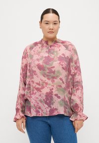 Blusa floreale in tonalità di rosa e verde, con scollatura arricciata e polsini con volant. Tessuto leggero e texturizzato con vestibilità morbida.